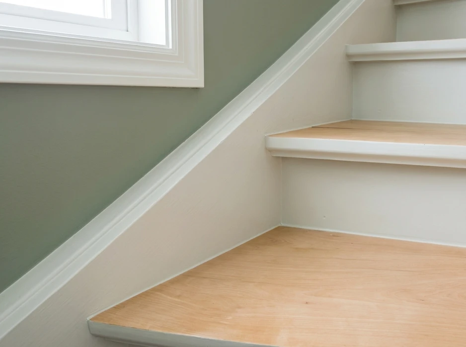 Escalier intérieur en bois clair avec contremarches et nez de marche peints en blanc