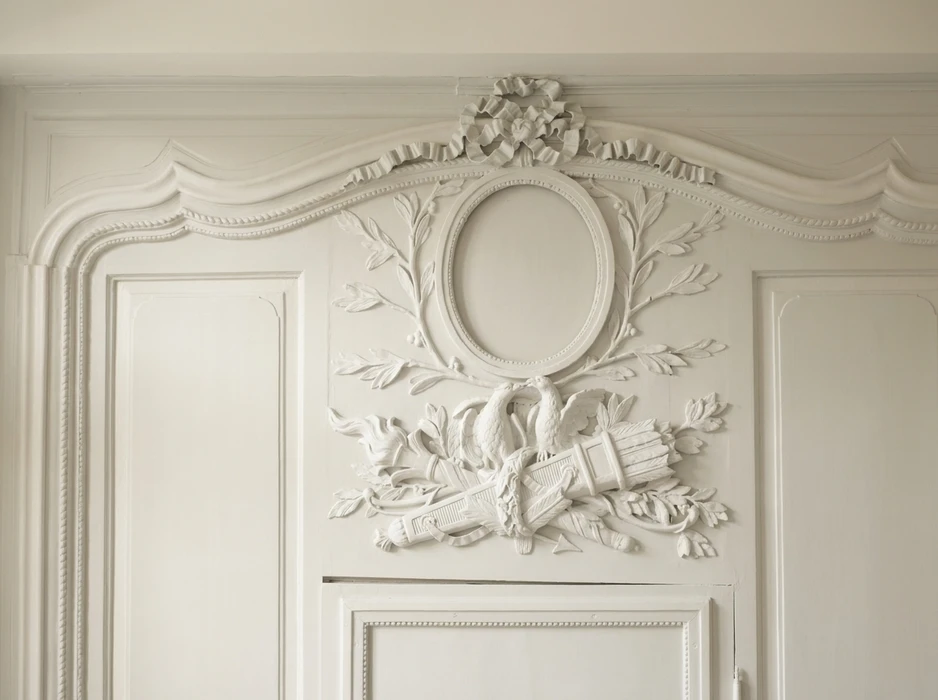 Décor architectural néoclassique en stuc blanc, surmontant une double porte