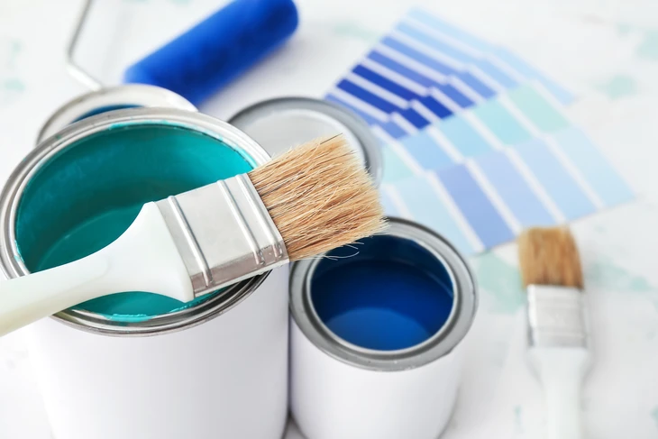 Chambre d'enfant moderne avec lit bleu, fresque murale représentant des montagnes colorées avec soleil orange, portant à vêtements en bois, étagères murales blanches, panier de jouets en osier, plante verte en pot jaune