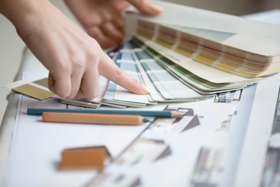 Intérieur lumineux avec main tenant un nuancier de couleurs déployé en éventail